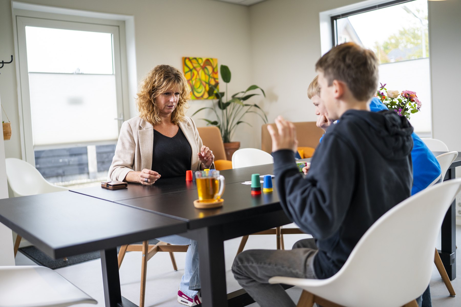 Behandelaar in gesprek met twee jongens aan tafel