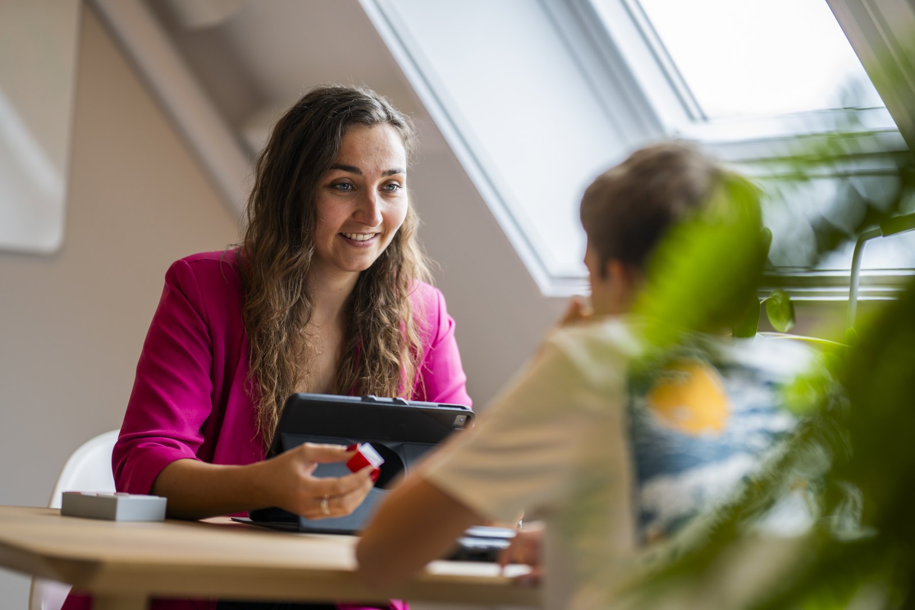 Behandelaar met tablet in gesprek met een kind