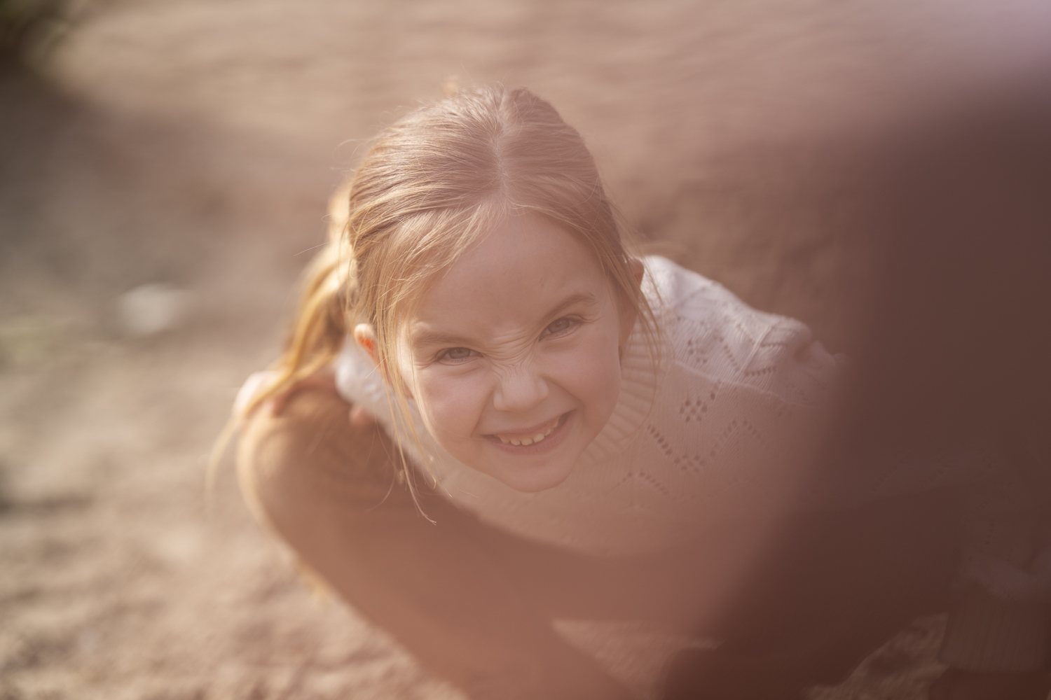 Meisje speelt lachend in het zand