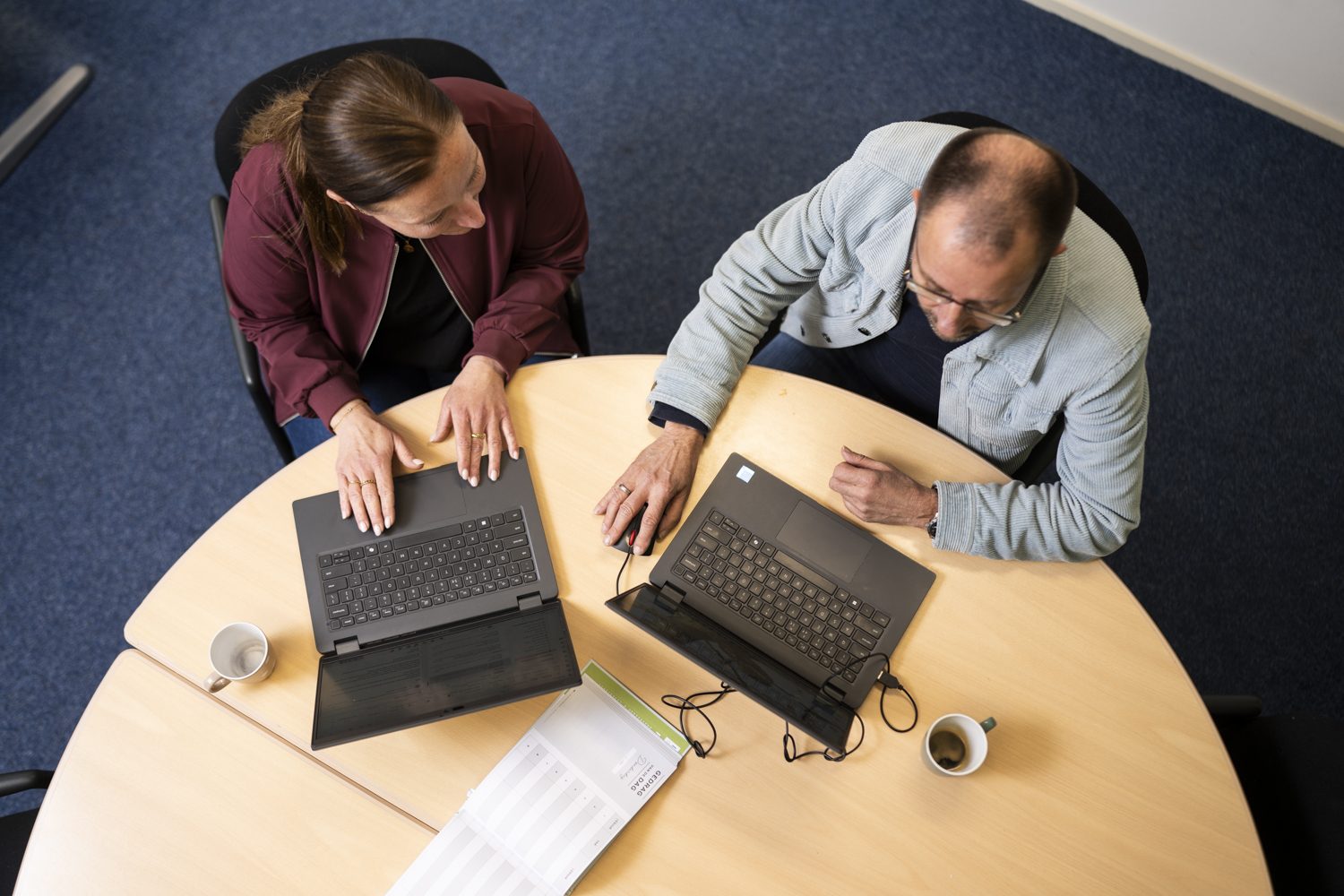 Twee medewerkers achter hun laptops